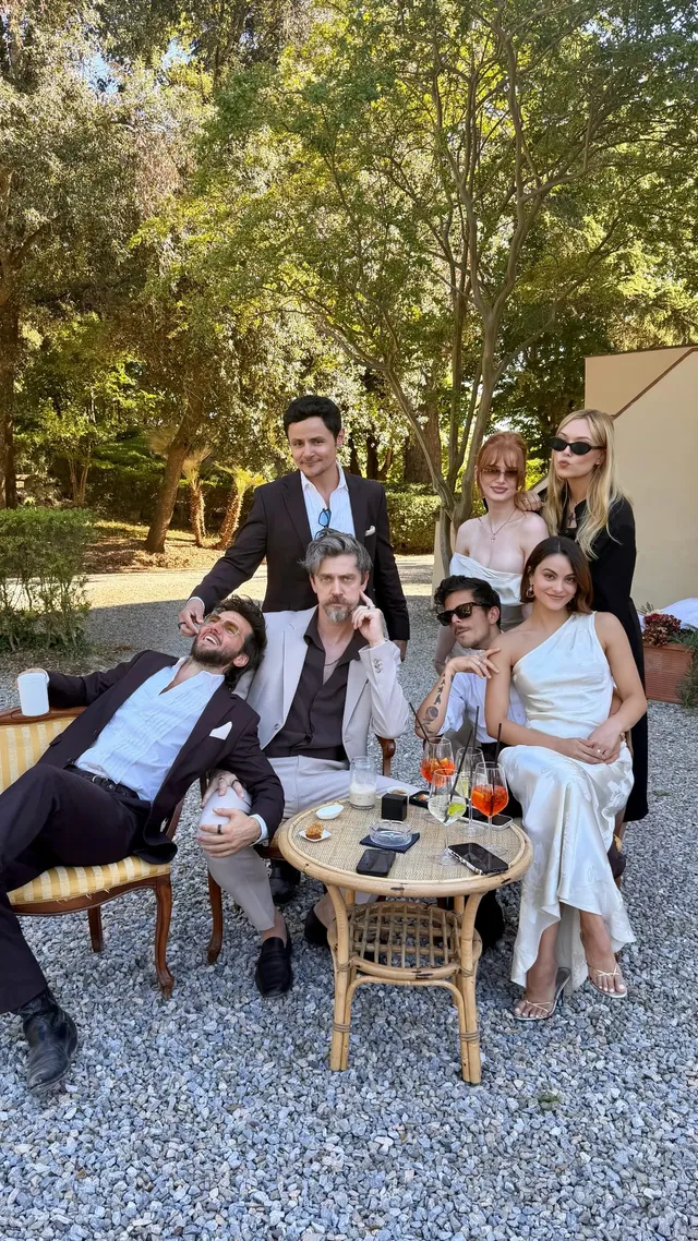 Camila Mendes sitting with a group in a garden.