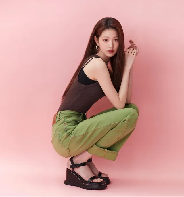 Jang Wonyoung crouching in green trousers and platform sandals.
