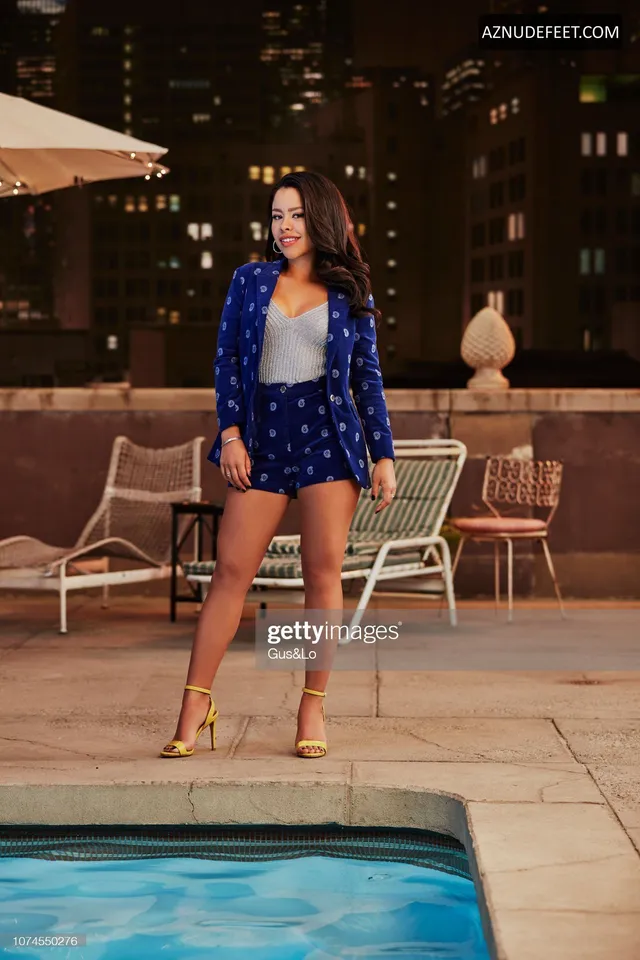 Cierra Ramirez in a blue patterned outfit and nude heels beside a pool at night.