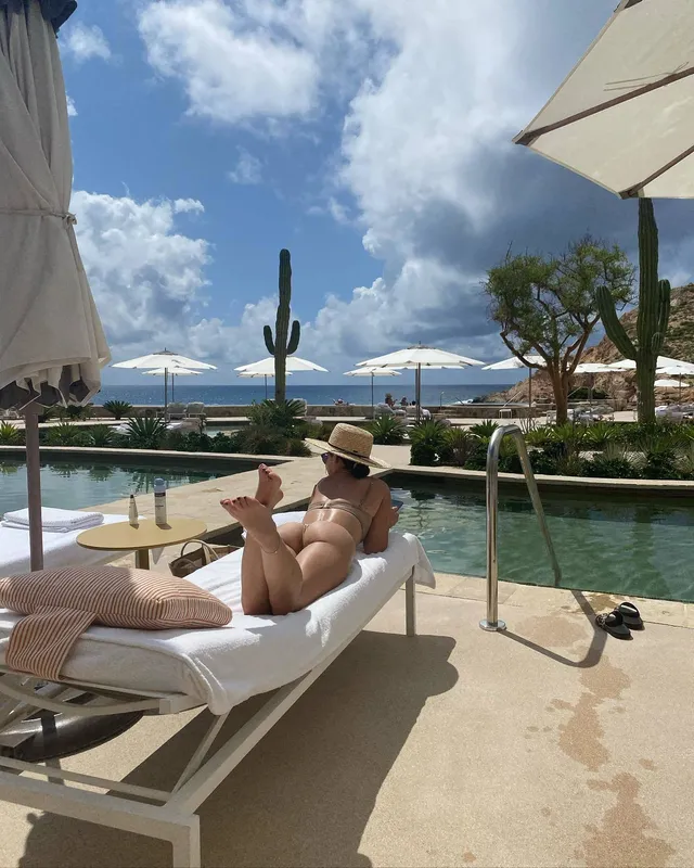 Lucy Hale relaxing beneath a poolside umbrella.