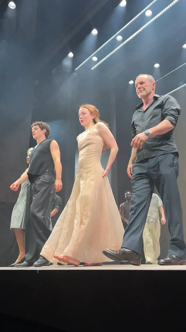Sadie Sink taking a barefoot bow with other performers onstage.