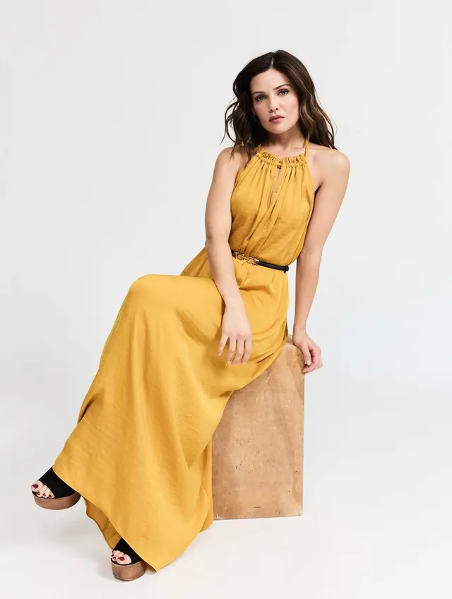 Danielle Campbell sitting for a portrait in a long yellow dress.