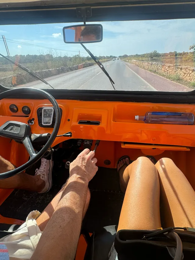 Gemma Chan riding in an orange vehicle in flat sandals.