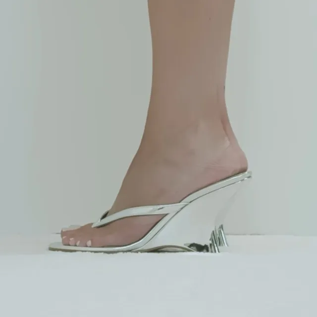 Kylie Jenner showing a white transparent wedge heel sandal.