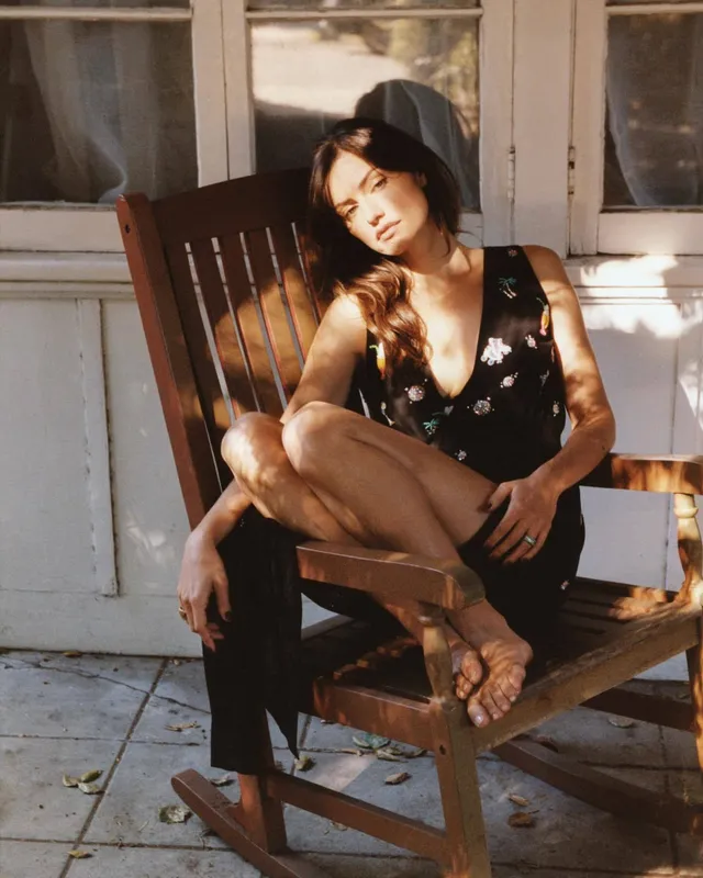 Phoebe Tonkin sitting on a wooden chair on a porch.