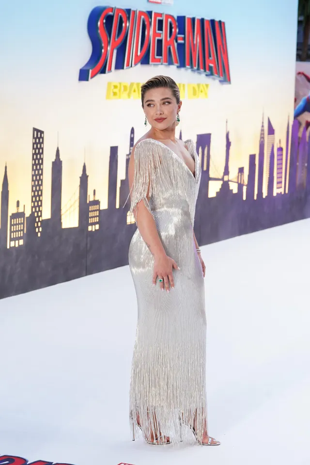 Florence Pugh posing in a silver gown and heels at a premiere.
