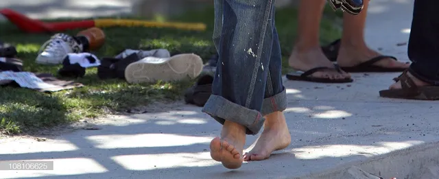 Gwen Stefani walking barefoot outdoors in rolled jeans.