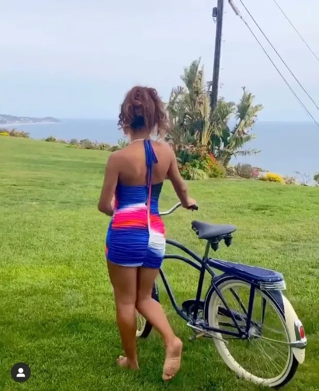 Sierra Capri standing barefoot with a bicycle near the coast.