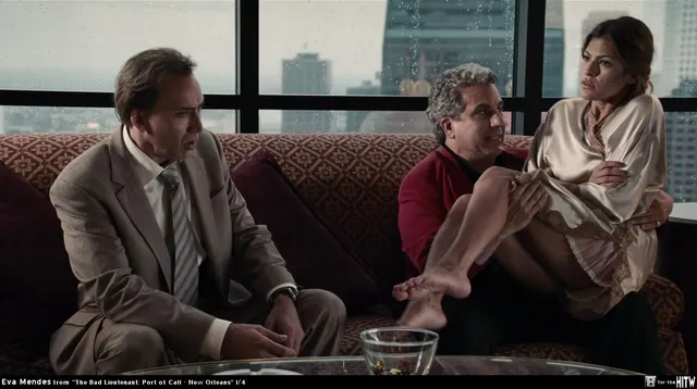 Eva Mendes sitting with two men in a screen scene.