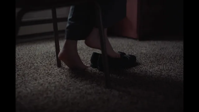 Daisy Ridley standing beside shoes in a dark screen scene.