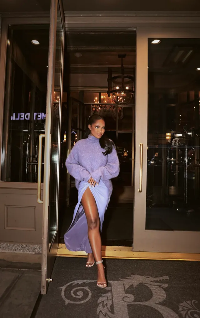 Ryan Destiny wearing a lavender dress and clear heels outside a building.
