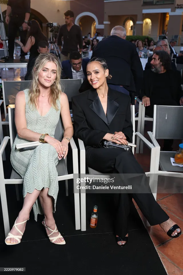 Nathalie Emmanuel sitting with a guest at a festival.