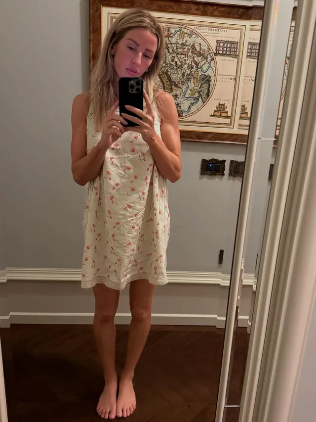 Ellie Goulding posing barefoot for a mirror photograph in a pale dress.