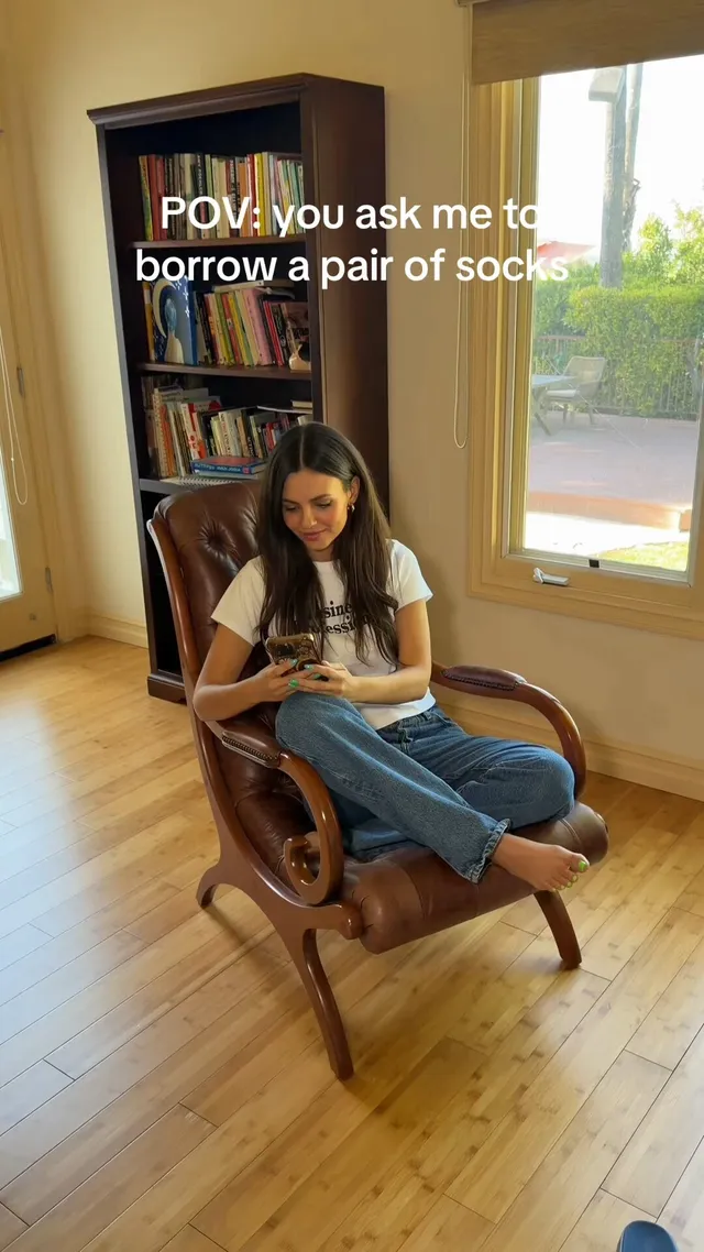 Victoria Justice sitting barefoot in a wooden chair.
