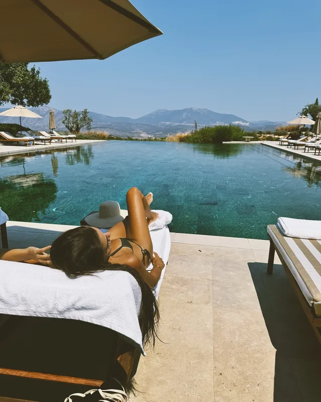 Hande Erçel reclining beside a swimming pool.