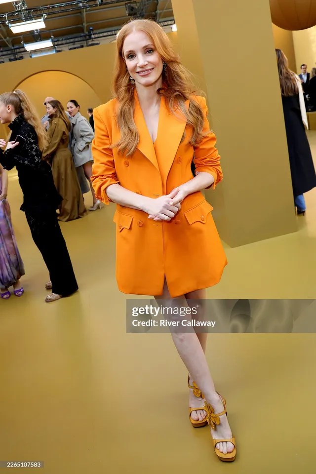 Jessica Chastain attending a fashion event in an orange jacket.