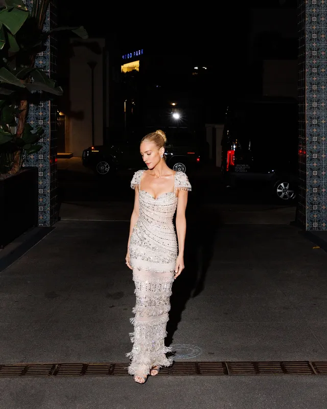 Brittany Snow walking outside in a pale embellished dress.