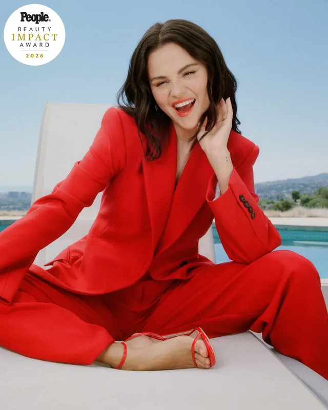 Selena Gomez: seated in a red suit and red heels.