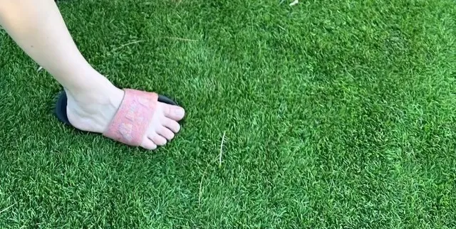 Kaley Cuoco wearing a pink slide on grass.