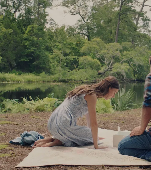 Daisy Edgar-Jones seated on a blanket beside a lake in a screen scene.