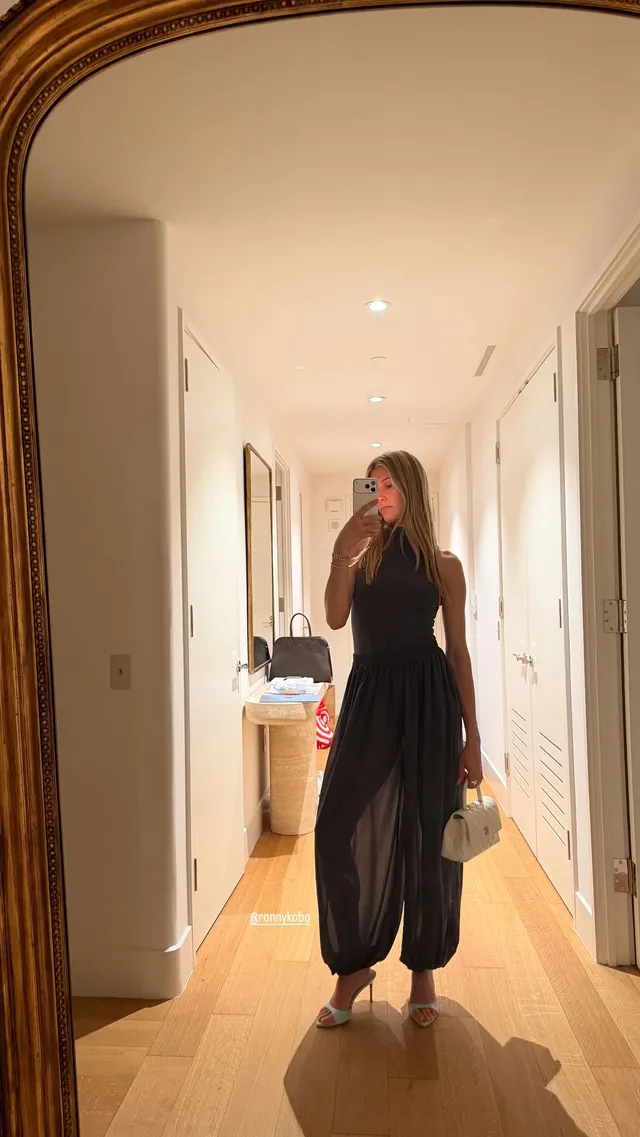 Eugenie Bouchard taking a barefoot mirror photograph in a long black dress.