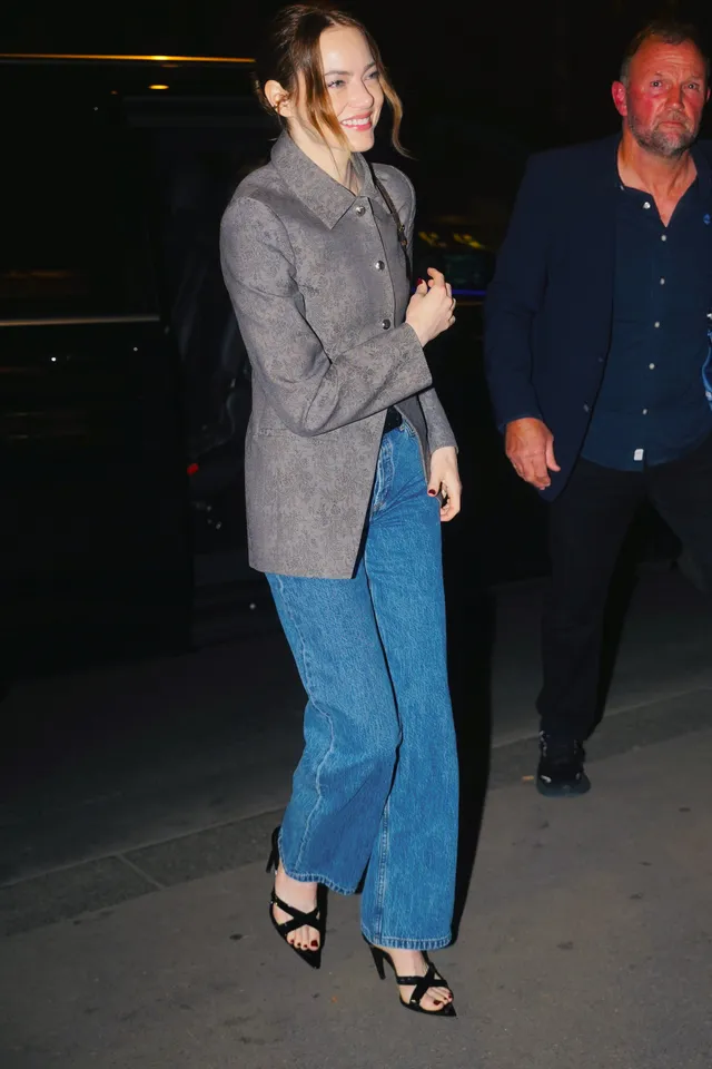 Emma Stone walking beside a man wearing jeans and black heels.