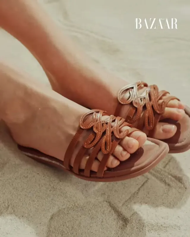 Jisoo showing brown flat sandals with decorative straps.