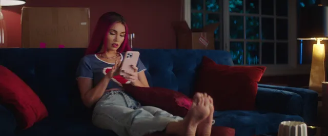 Megan Fox: reclining barefoot on a sofa while holding a phone.