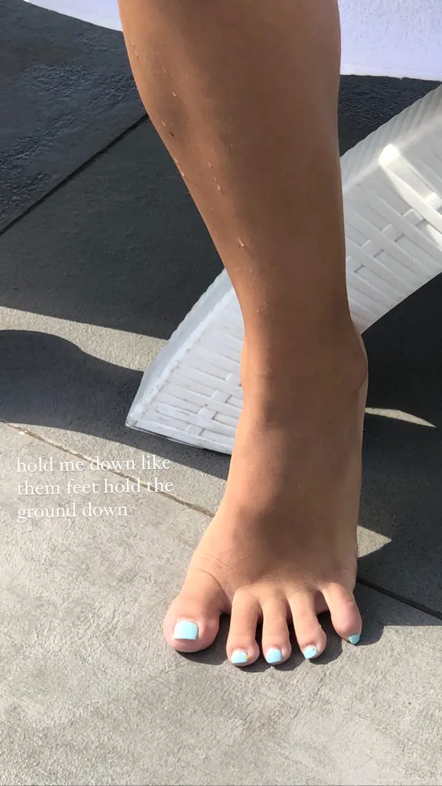 Isabela Merced showing a bare foot with pale blue toenail polish.