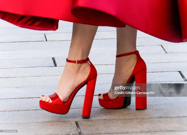 Anne Hathaway wearing red platform heels beneath a red dress.