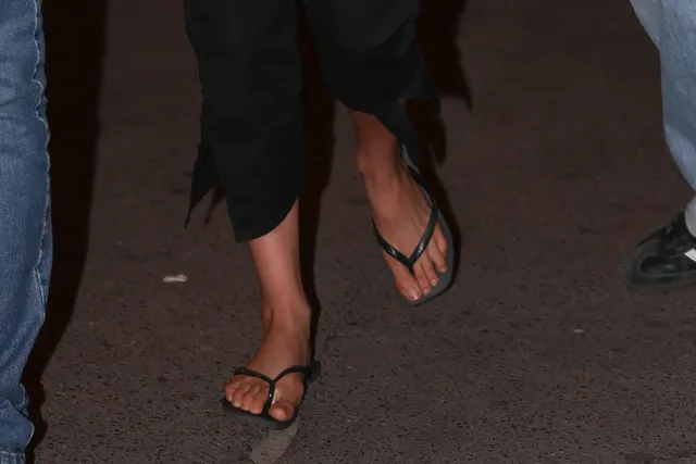 Jenna Ortega: close view of black flip-flops at an evening event.