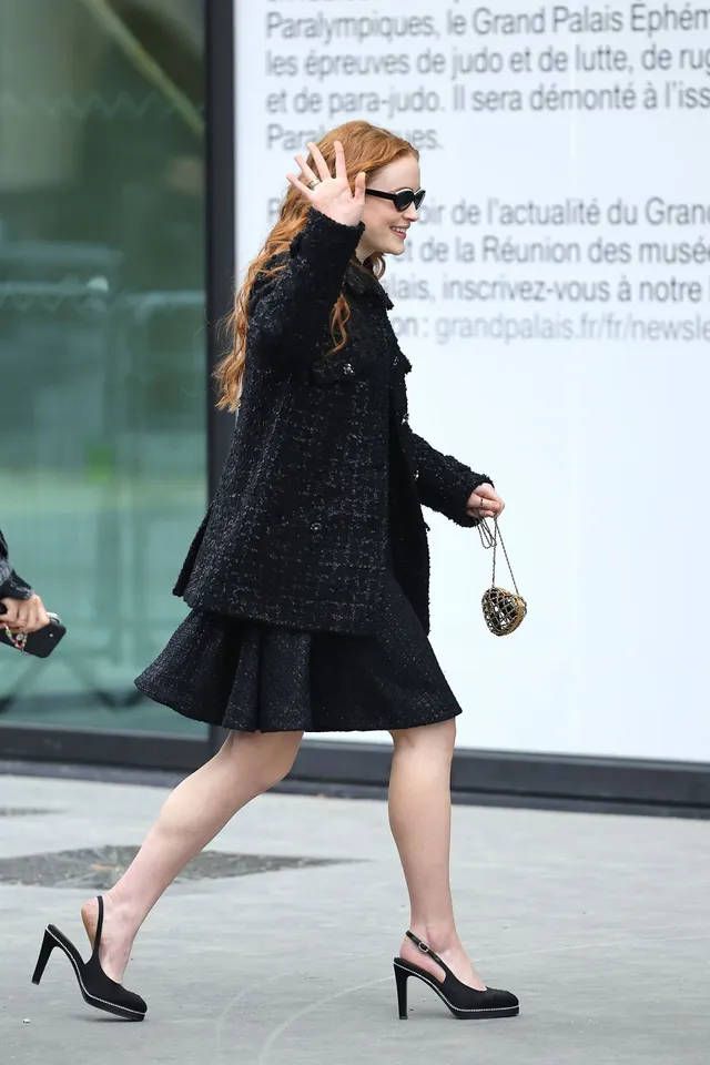 Sadie Sink walking outdoors in a black outfit and slingback heels.