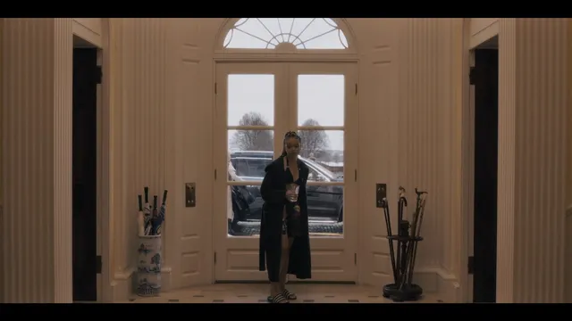 Whitney Peak standing indoors in a dark outfit and heels in a scene.