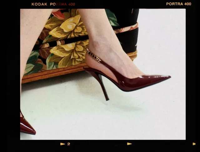 Kirsten Dunst wearing a burgundy pointed heel in a fashion detail image.