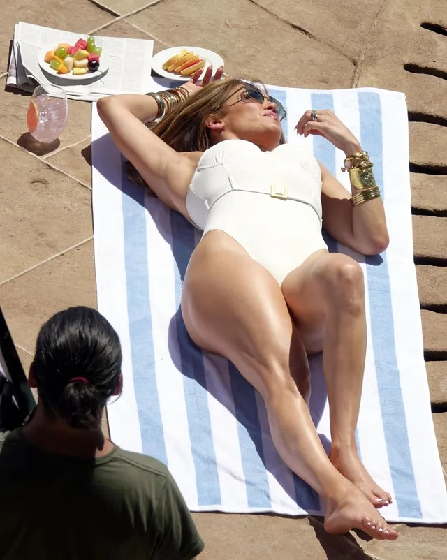 Jennifer Lopez a white swimsuit while reclining on a sunbed.