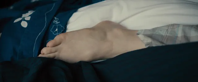 Rachel McAdams with bare feet resting beside another person in a screen image.