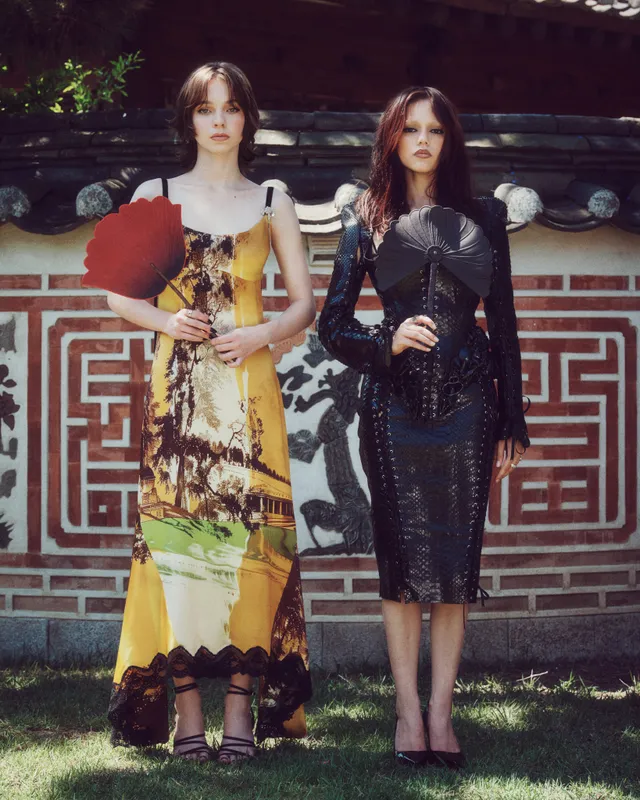 Emma Myers posing beside another woman outdoors in a patterned dress.