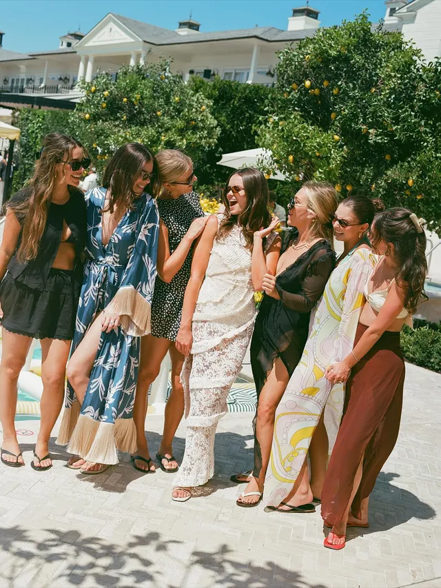 Hailee Steinfeld posing outdoors with friends in a dress and heels.