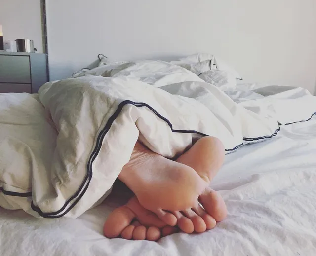 Elsa Hosk resting her bare feet beneath bedding.
