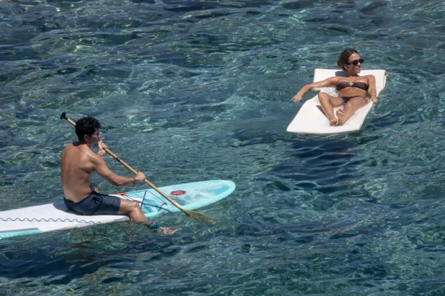 Jessica Alba floating barefoot on a white board beside the sea.