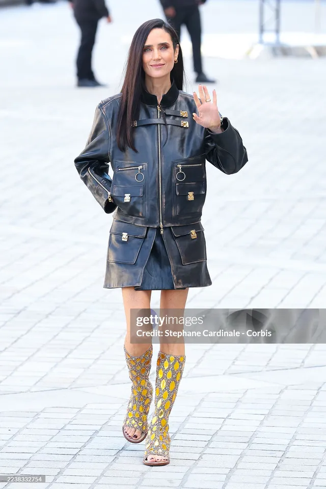 Jennifer Connelly posing at a fashion event in a denim outfit.