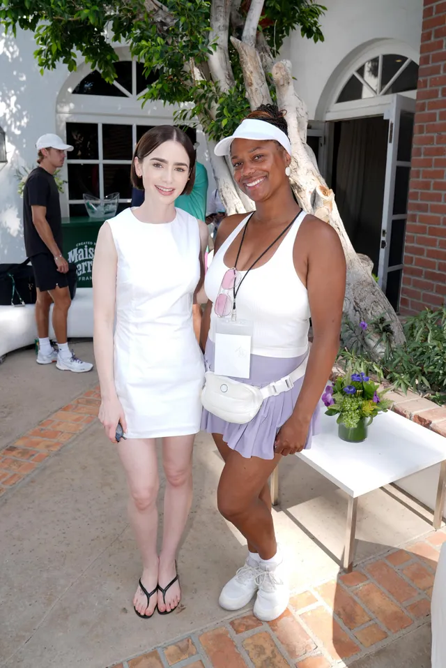 Lily Collins posing with a friend in a white dress and flip-flops.