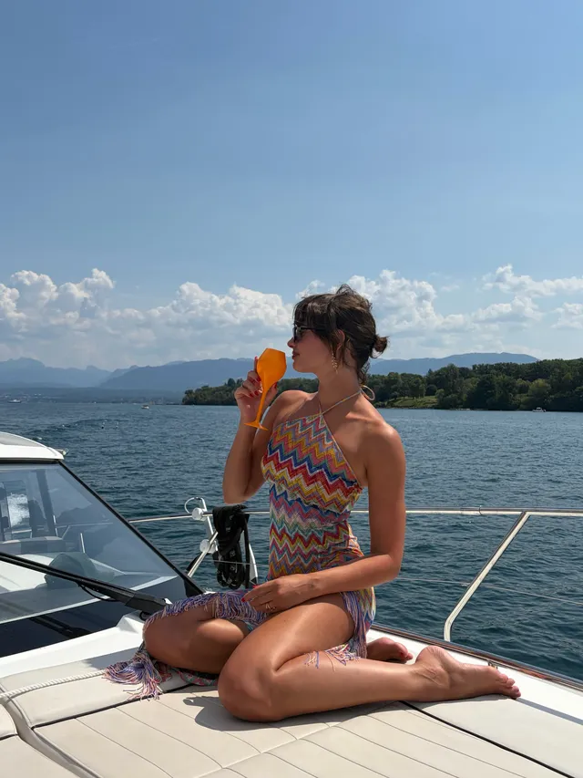Taylor Hill kneeling barefoot on a boat deck in patterned swimwear.