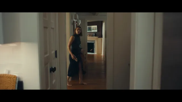 Jessica Biel a screen scene walking through a hallway in a dark dress.