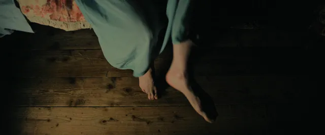 Daisy Ridley resting her bare feet on a floor in a screen scene.
