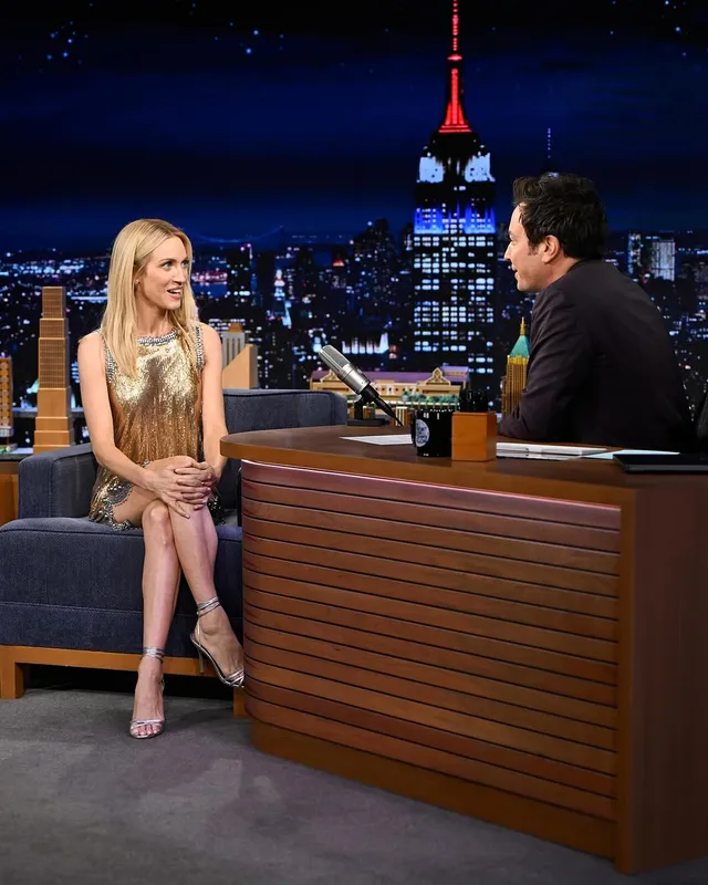 Brittany Snow sitting at a television interview in a metallic dress.