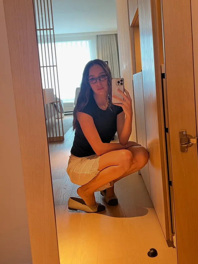 Alycia Debnam-Carey taking a crouched mirror portrait in a dark top and shorts.
