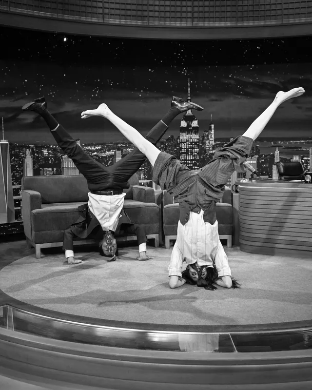 Cara Delevingne balancing upside down with a host on a television set.