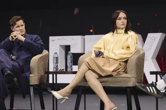 Olivia Cooke sitting with another speaker onstage.