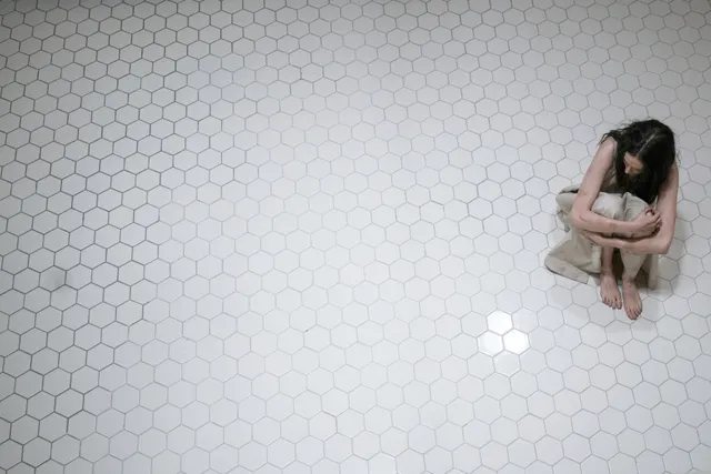 Eva Green sitting barefoot against a tiled wall.